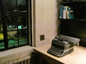 A typewriter sitting on a desk next to a window